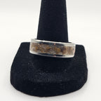 Silver ring on a black stand against a white background