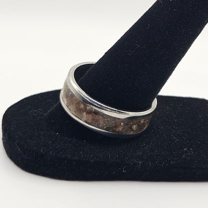 Silver ring on a black velvet stand against a white background