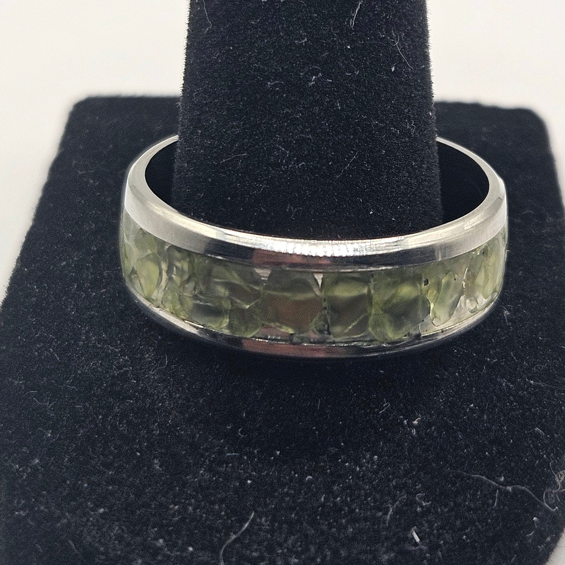 Silver ring on a black jewelry stand against a white background