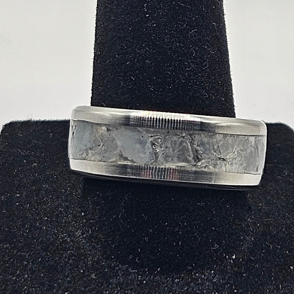 Silver ring on a black cushion against a white background