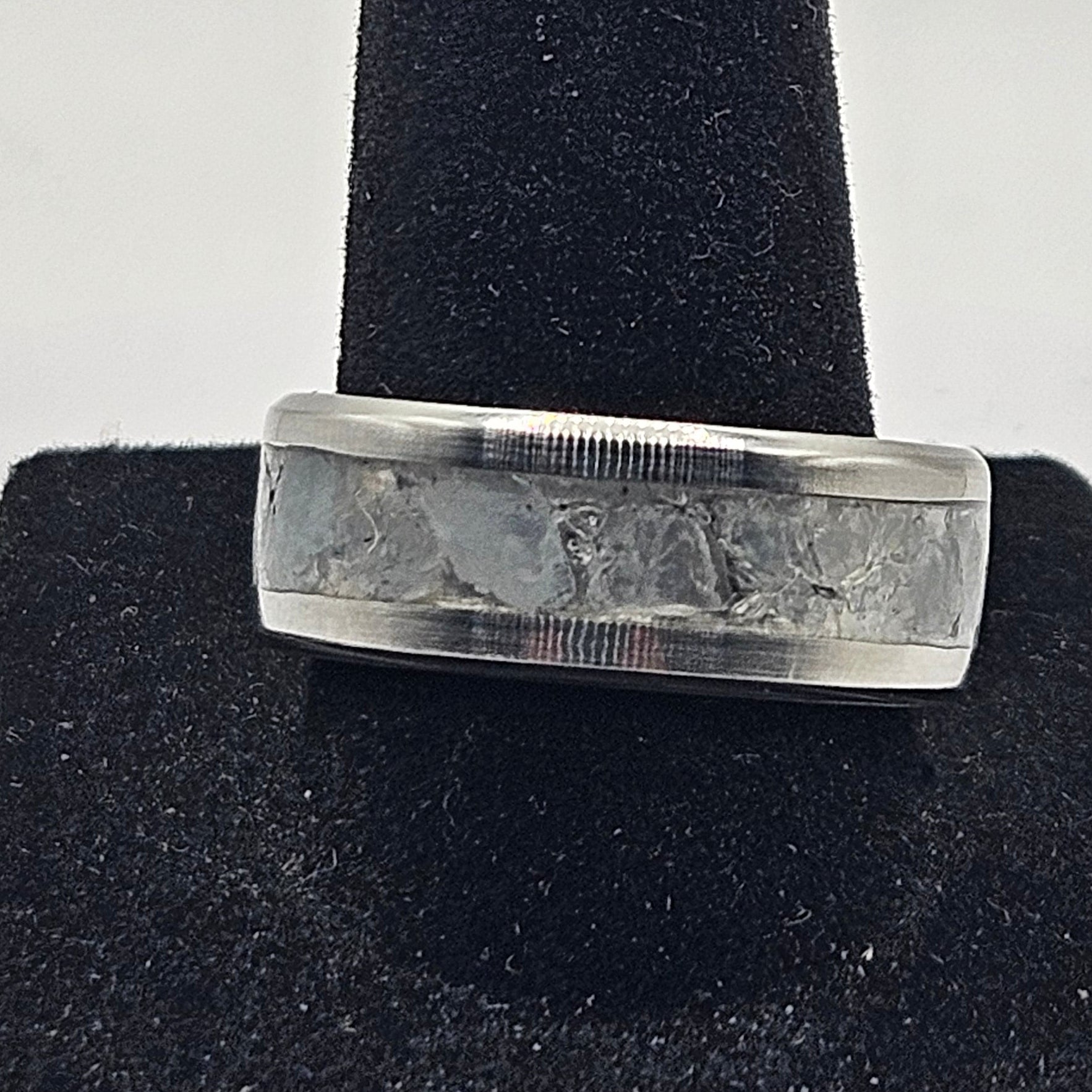 Silver ring on a black cushion against a white background