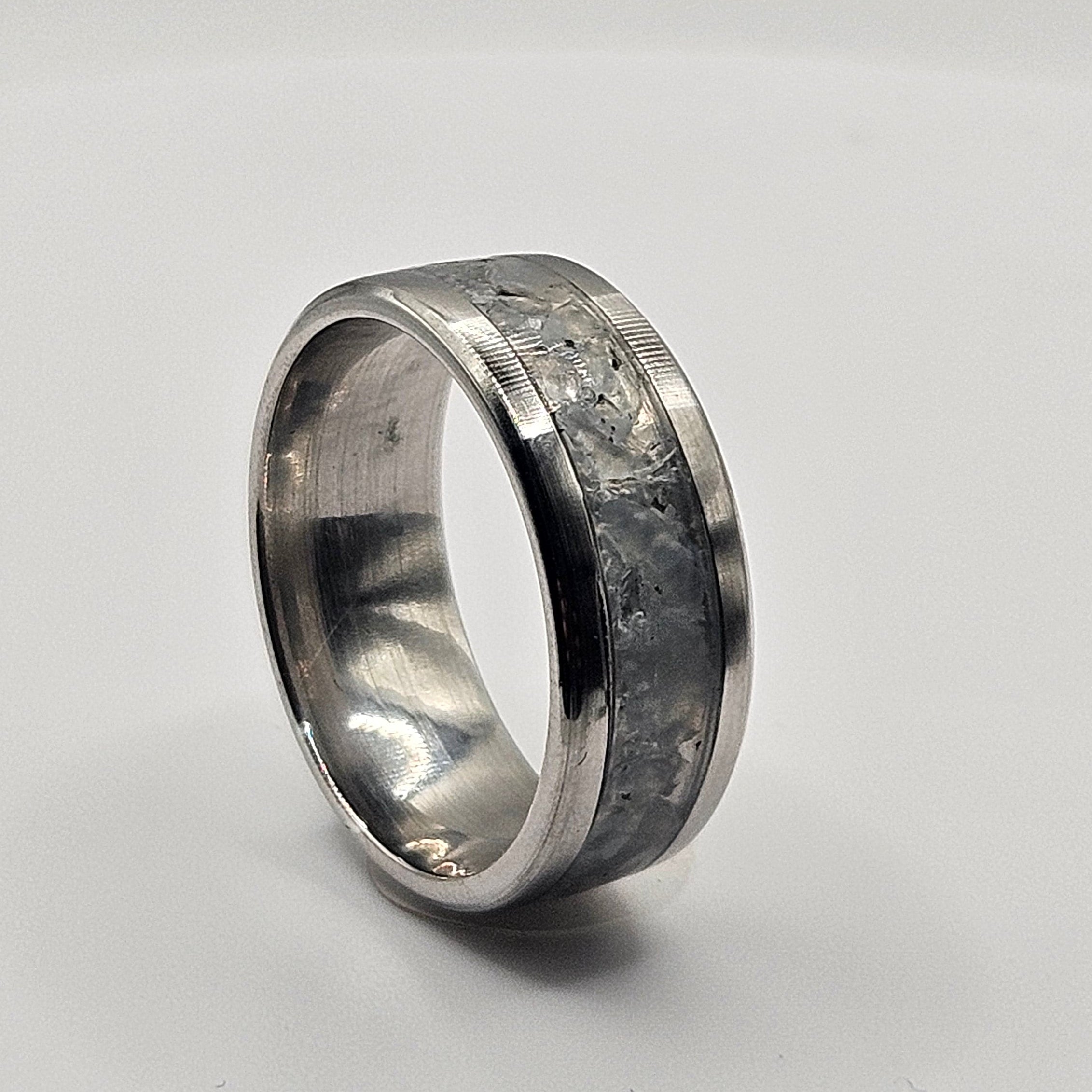 Silver ring with textured band on a white background