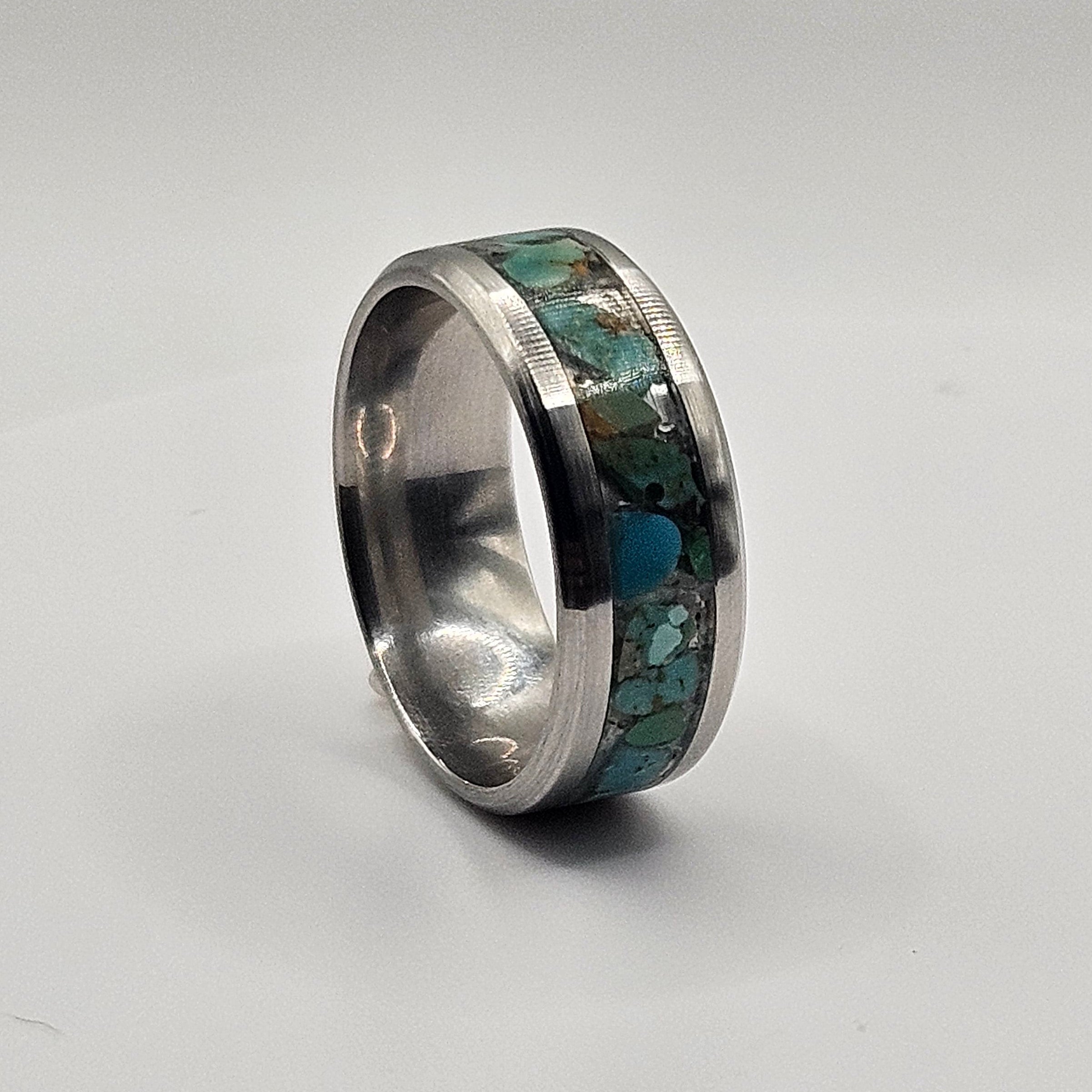 Silver ring with embedded greenstone on a white background
