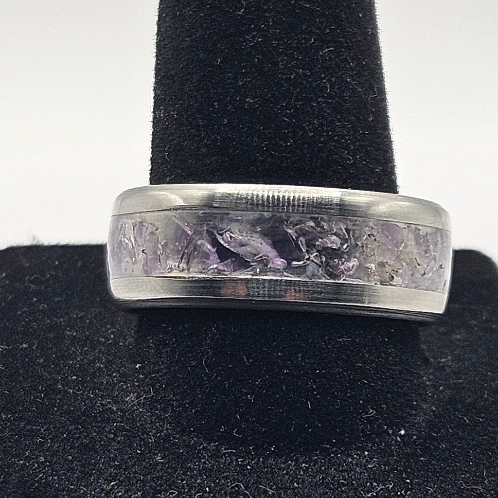 Silver ring with engraved design on a black stand against a white background