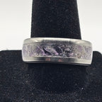 Silver ring with engraved design on a black stand against a white background