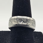 Silver ring with a textured band on a black velvet stand against a white background