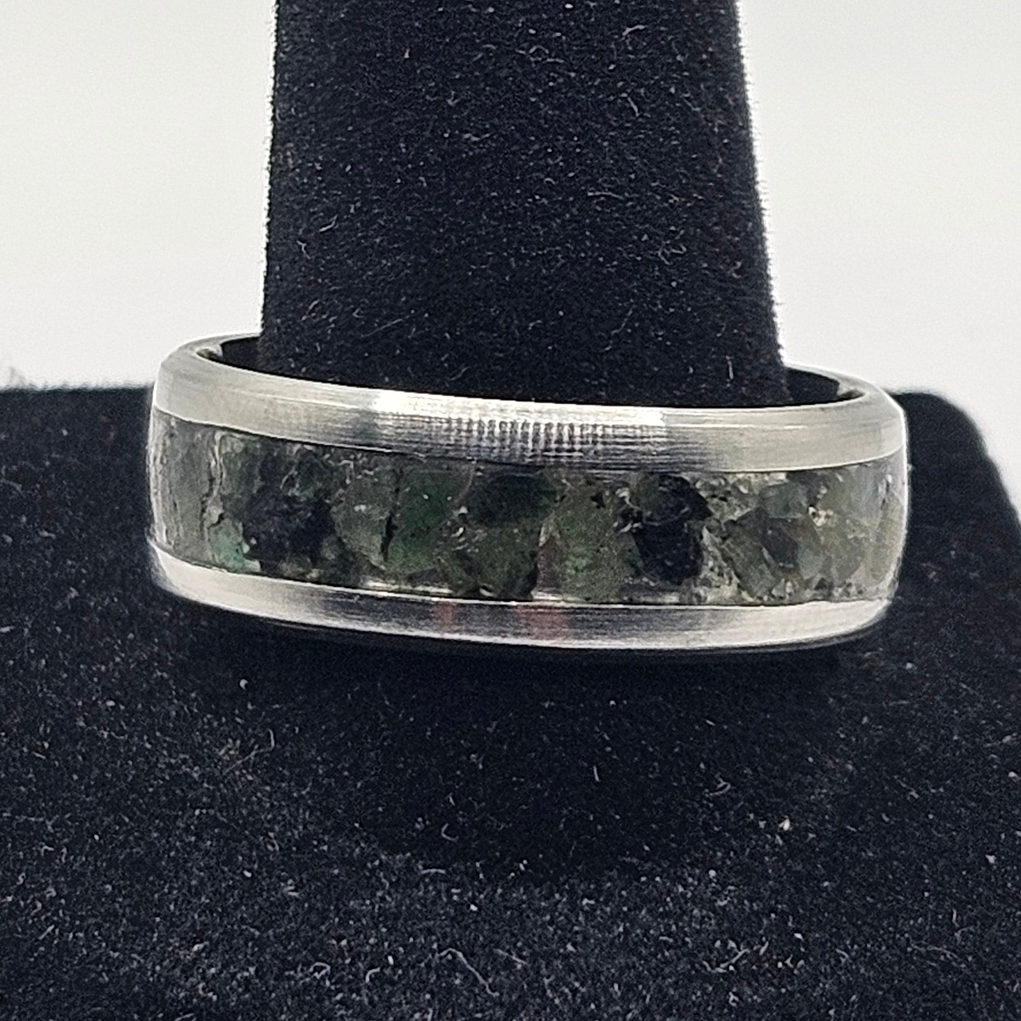 Silver ring on a black velvet stand against a white background