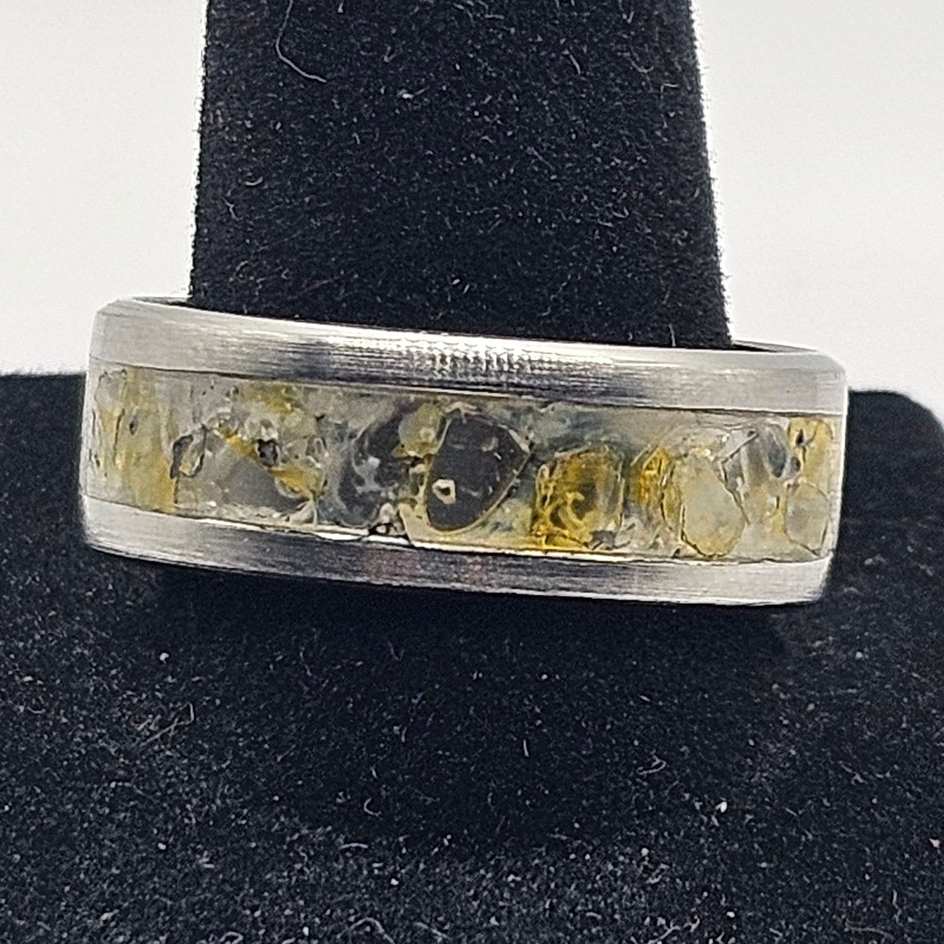 Silver ring with embedded stones on a black velvet stand