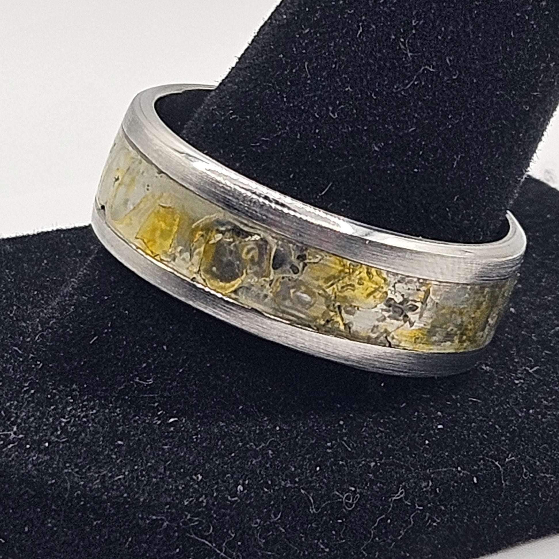 Silver ring with embedded stones on a black stand against a white background