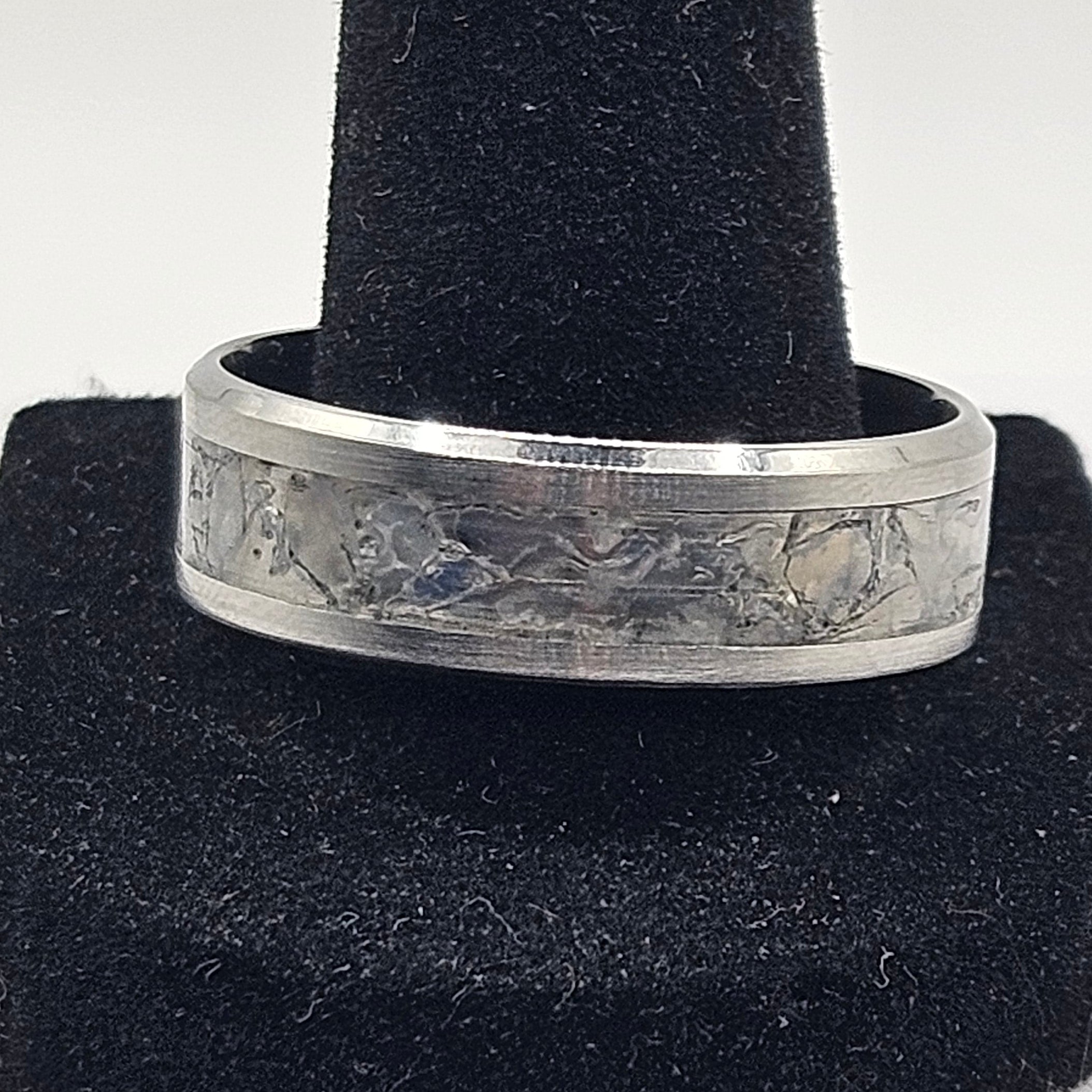 Silver ring on a black velvet stand against a white background