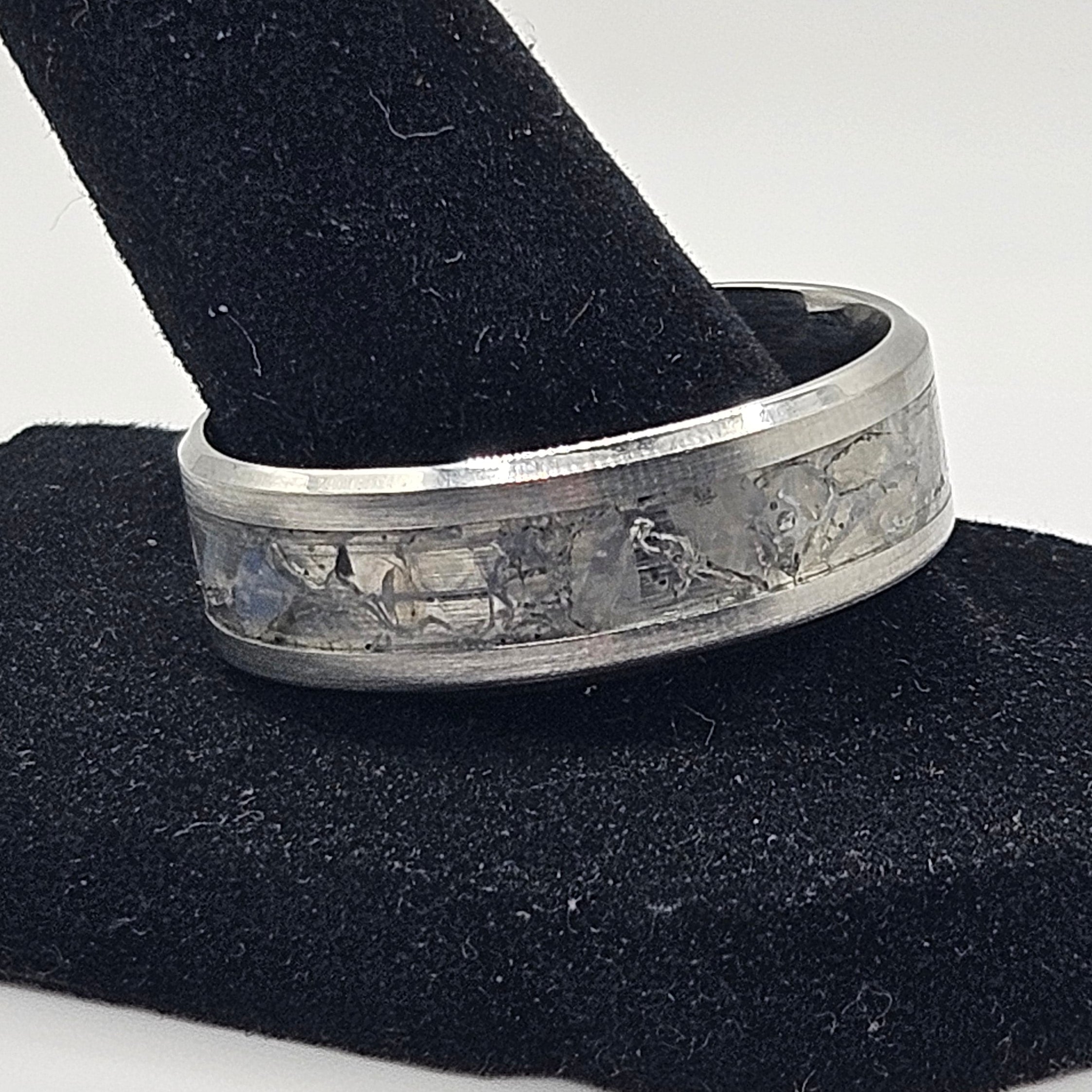 Silver ring on a black stand against a white background