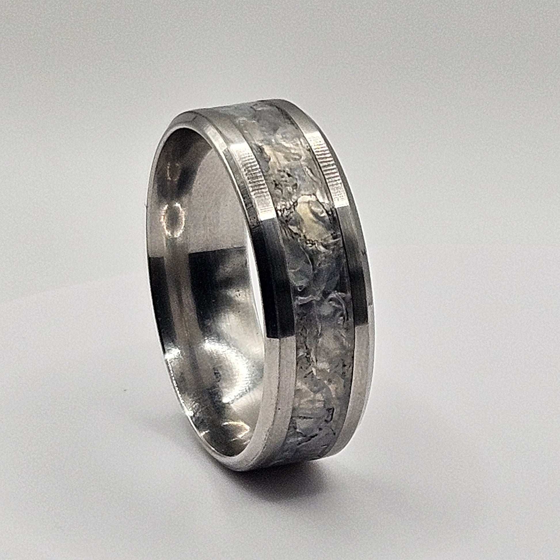 Silver ring with a clear stone inlay on a light gray background