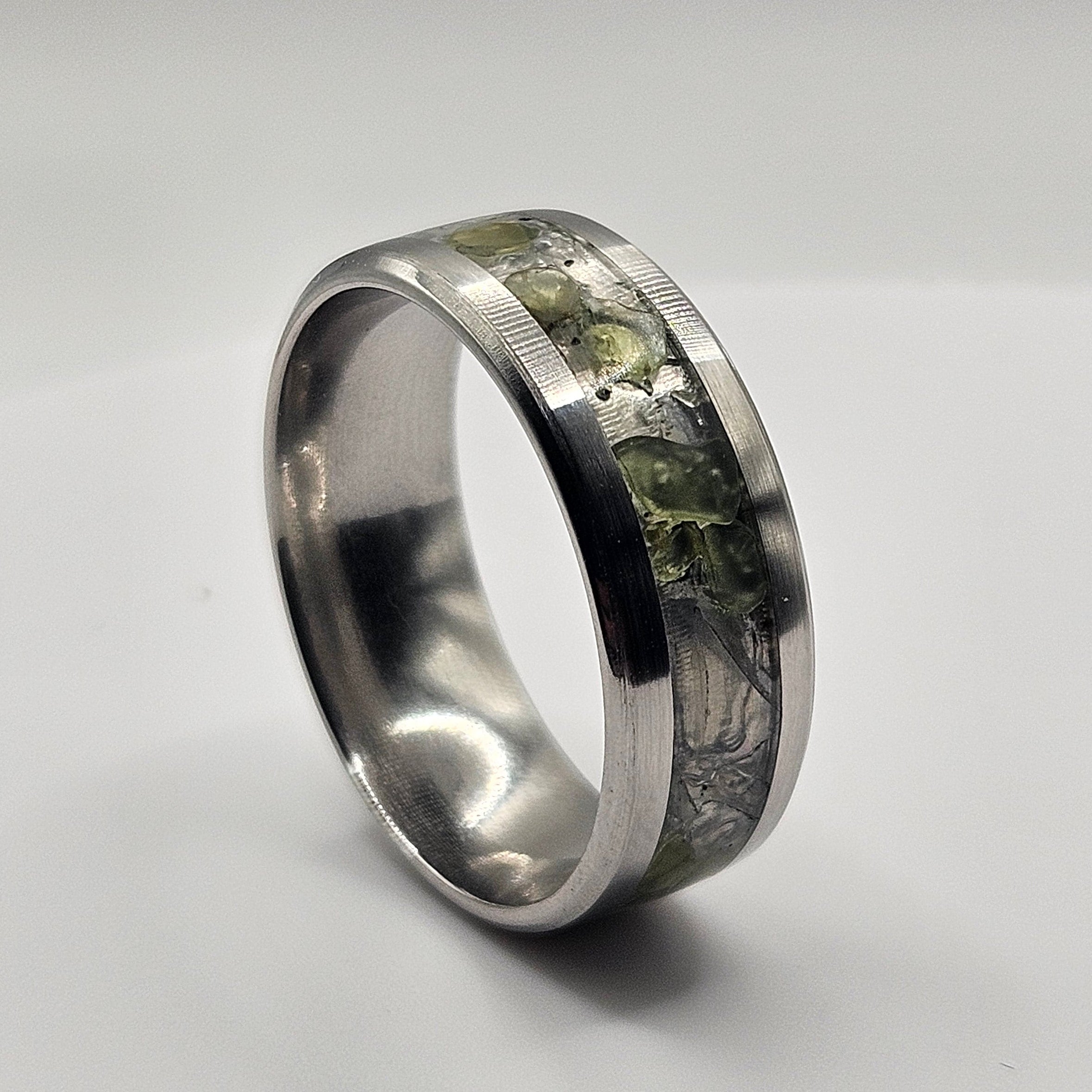 Silver ring with embedded material on a light gray background