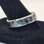 Silver ring on a black stand with a white background