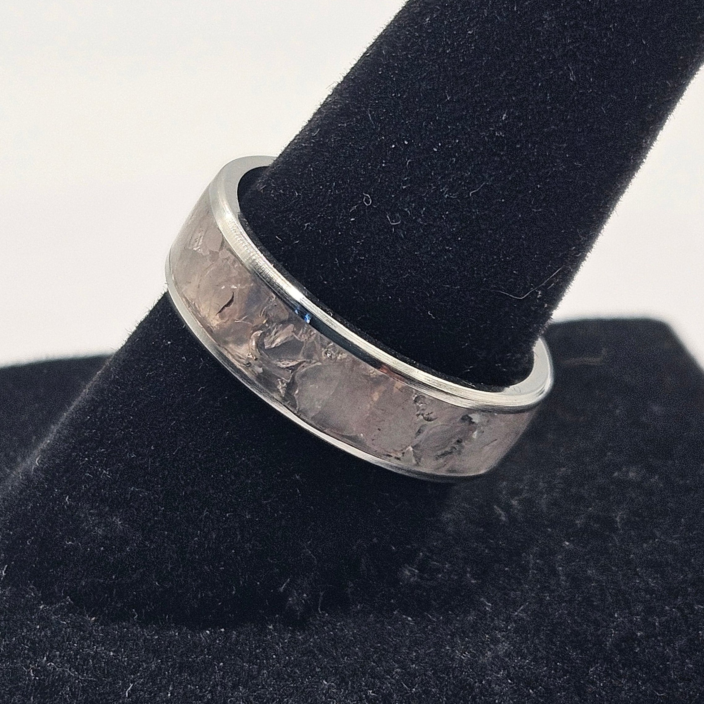 Silver ring on a black stand with a white background