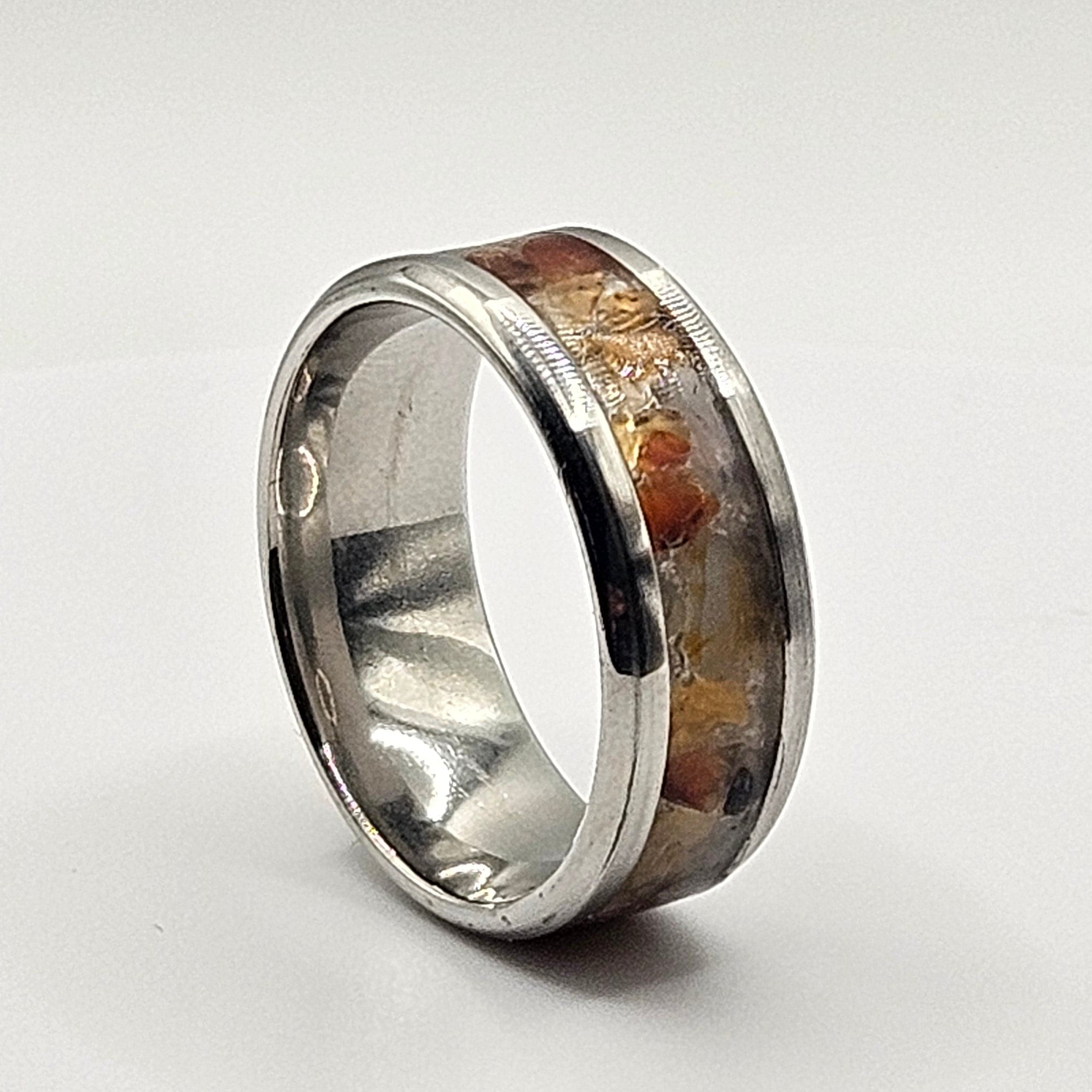 Silver ring with embedded material on a light gray background